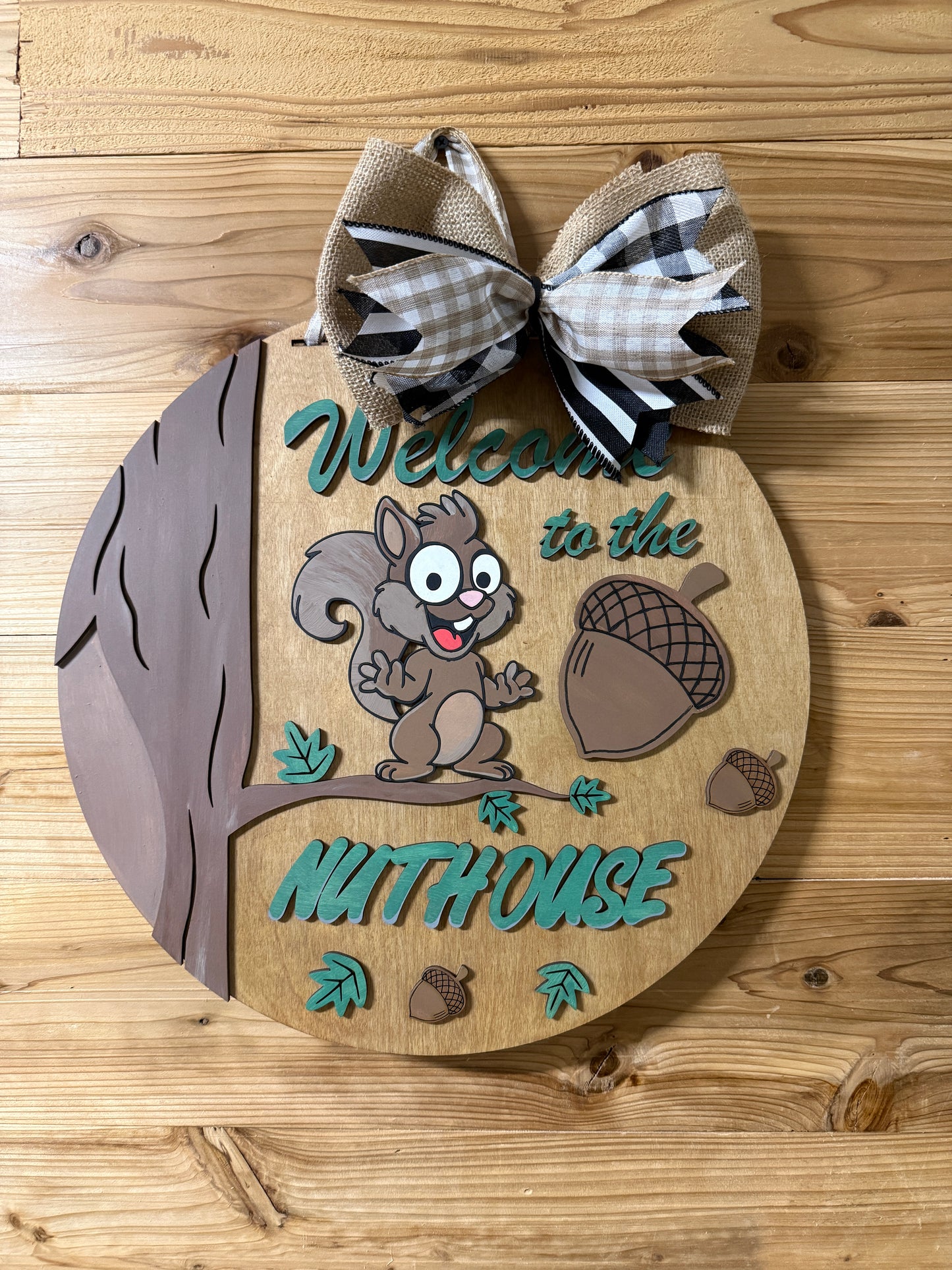Wooden door hanger with a cartoon squirrel and acorns on a wooden surface