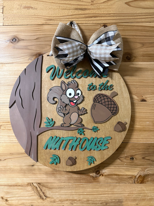 Wooden door hanger with a cartoon squirrel and acorns on a wooden surface